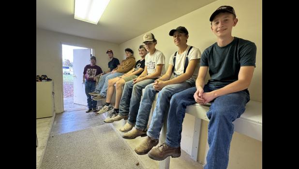 Showing off their work: students in the Carpentry 1 & 2 class sit on the shelves they built for G&W Foods’ corporate offices. photo provided