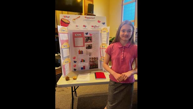 Molly Dix is pictured above with her second place Science Fair entry on her findings on the difference of using baking powder and baking soda in her muffins. Dix tied for second place. photo provided