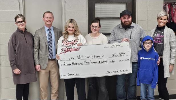 Lexi Williams Fundraiser: The West Plains School District presented Lexi Williams and her family with a $15,322 check to help her with medical costs. Williams, a student at West Plains High, was paralyzed last year while she fought an infection. The district hosted a series of fundraising events to help the family, including selling over 200 racks of ribs, selling T-shirts, and holding a dessert auction. Standing left to right: Board President Cindy Tyree, High School Principal Ryan Smith, Lexi Williams, Kayla Williams, Michael Williams, Roman Williams, and Athletics Director Dr. Ashley Cooley. Not pictured was the family's other daughter, Lilly. Howell County News/Nate Hudson