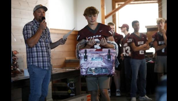 Brady James holds up a maroon-and-white cooler for auction while auctioneer Eric King takes bids. courtesy of Shawana Cox