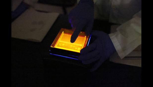 Dr. Sharath Rongali, assistant professor of biology at Missouri State University-West Plains (MSU-WP), and his students Juliana Lopez, Lebanon, and Macie Tate, Mansfield, use a blue light to analyze the agarose gel to identify DNA bands as part of their antibiotic-resistance bacterial research project. photo courtesy of MSU-WP